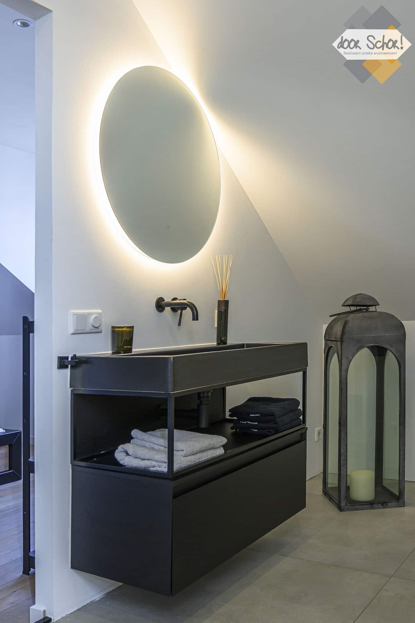 Zwart badkamer meubel met een ronde spiegels met verlichting erachter
